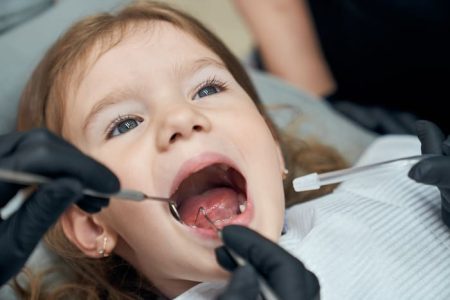 dentista-examinando-el-estado-de-los-dientes-del-pequeno-paciente Tratamientos restauradores